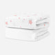 Two folded crib sheets, one white with pink stars and one solid white, stacked on a white background. skip
