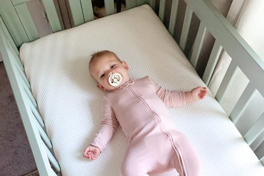 baby sucking on a pacifier in a crib