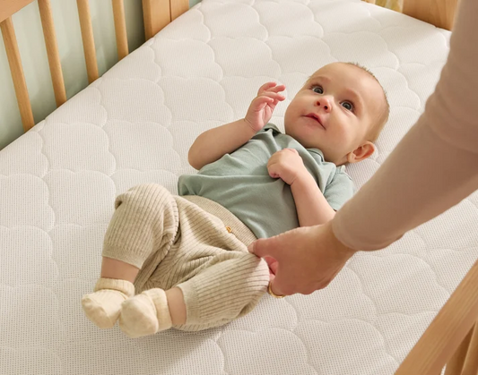baby laying on crib mattress