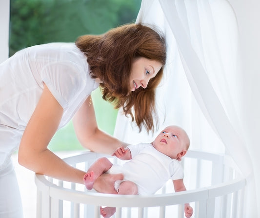 Mom putting baby into a potable crib