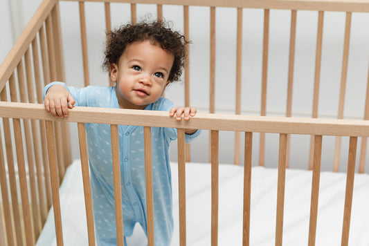 baby using a sleep sack while standing in a crib
