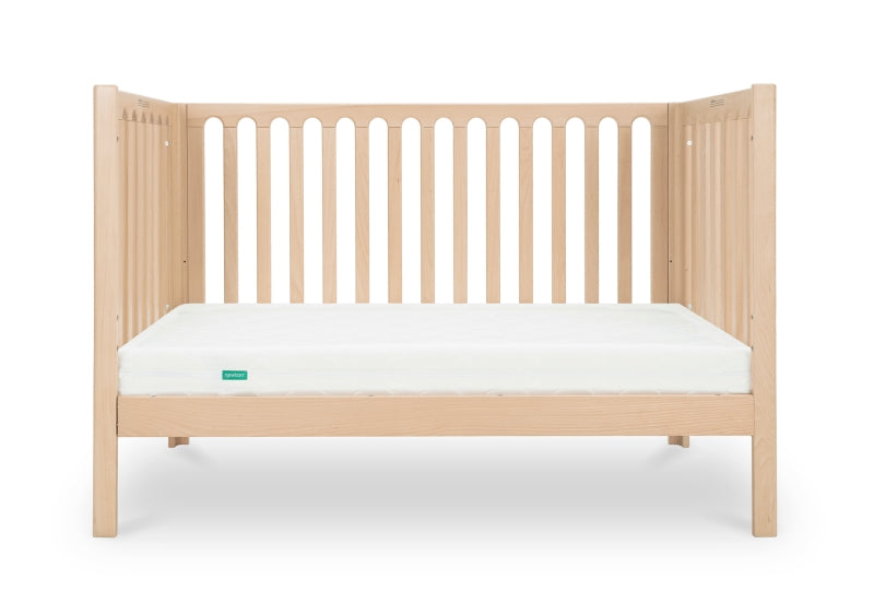 A modern wooden crib with vertical slats and a white mattress, isolated on a white background.