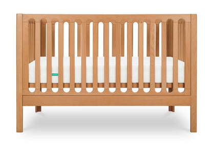Modern wooden crib with visible Newton mattress, positioned against a white background.