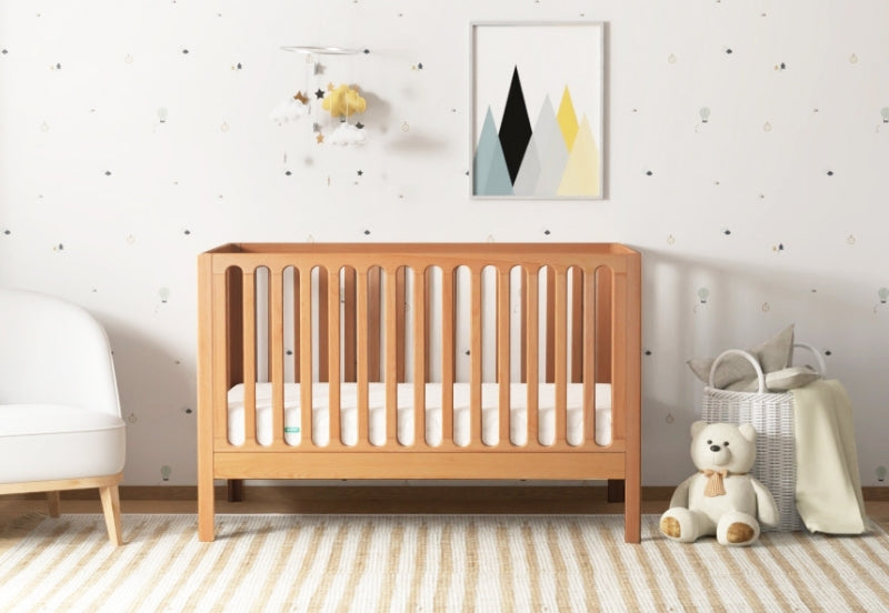 A serene nursery featuring a wooden crib, a cozy white armchair, a plush teddy bear, and decorative accents like a cloud and star mobile and abstract wall art. 999-8420-CST