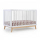 The dadada baby Soho Convertible Crib features white slatted sides, a sturdy beechwood frame, and includes a Newton crib mattress with a pink and white patterned sheet, all set against a plain white background. 500-8220-NAW