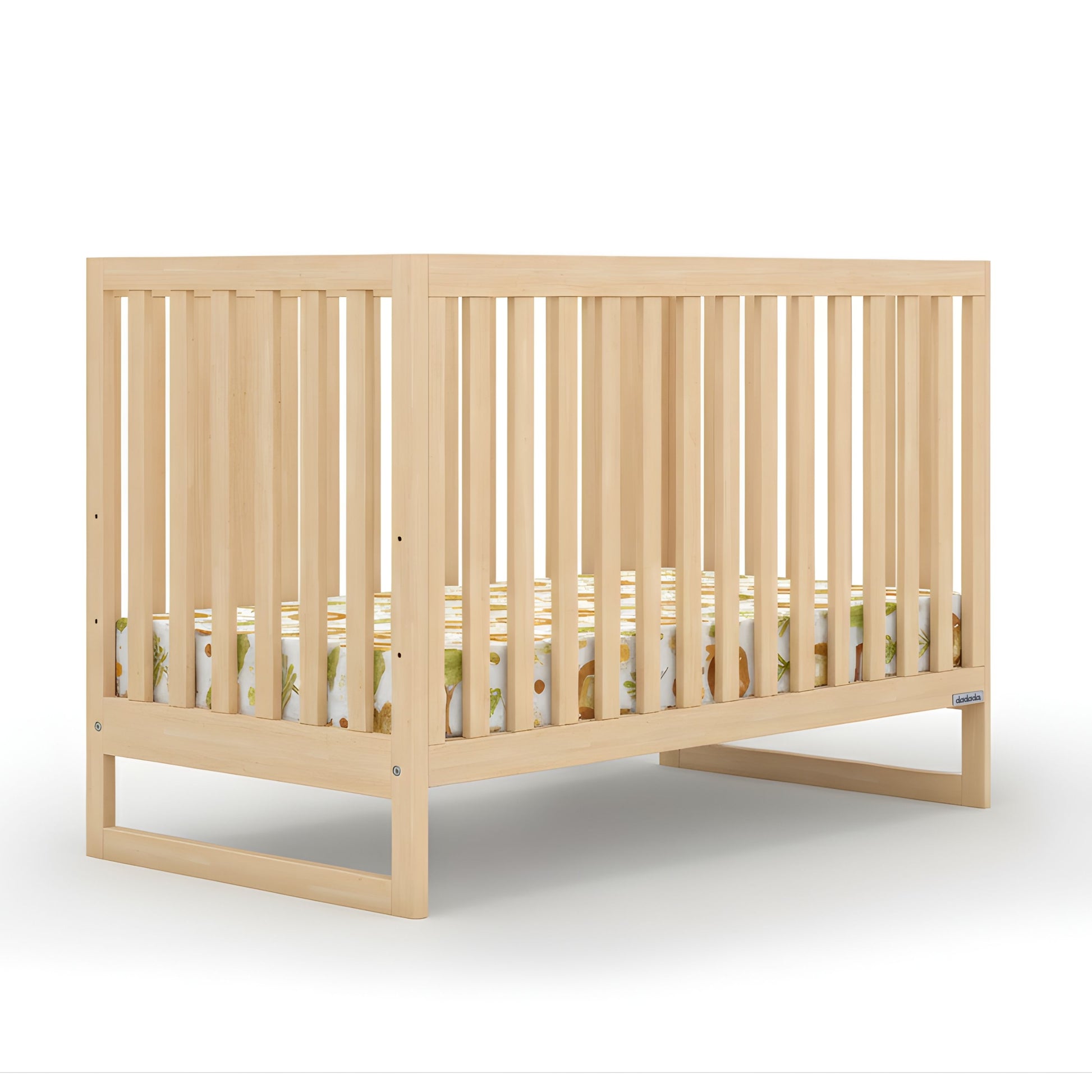 The dadada baby Austin Convertible Crib features light wood, vertical slats on all sides, and a modern design. A patterned crib mattress with animal prints sits inside, set against a plain white background. 500-8200-NAT