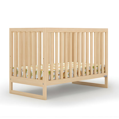 The dadada baby Austin Convertible Crib features light wood, vertical slats on all sides, and a modern design. A patterned crib mattress with animal prints sits inside, set against a plain white background. 500-8200-NAT