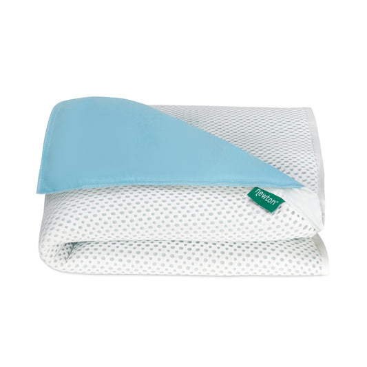 The Essential Waterproof Crib Pad by Newton Baby is a white, gray-dotted blanket with a light blue corner and green Newton tag—ideal as a breathable mattress pad or for layering over your crib mattress.