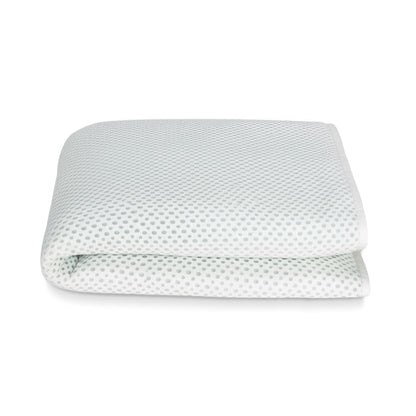 The Newton Baby Essential Waterproof Crib Pad, featuring a white breathable design with subtle gray dots, is shown folded against a plain white background.