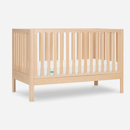 Simple wooden crib with slatted sides on a plain white background, featuring a small green logo at one end.