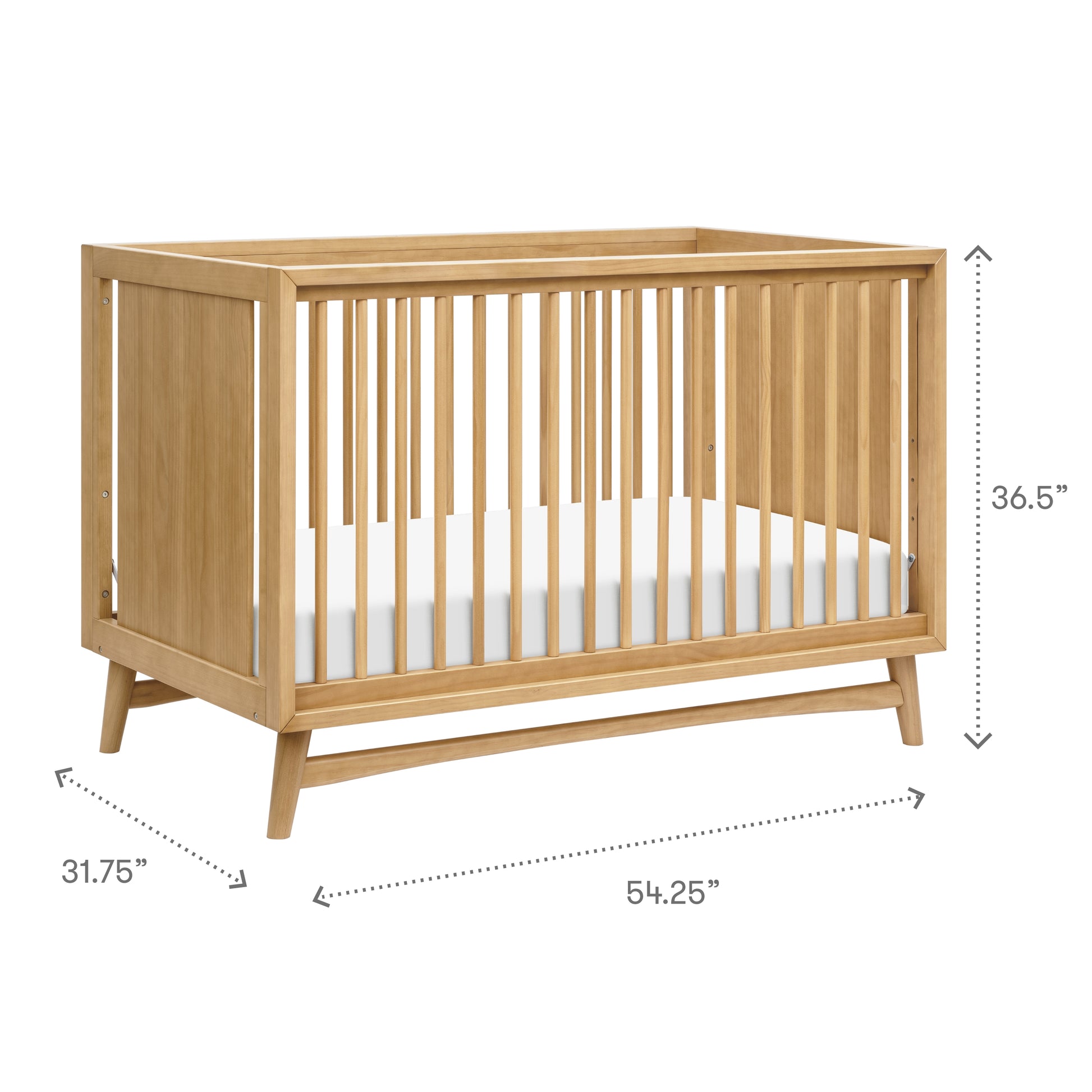 The Babyletto Peggy Convertible Crib features light wood, angled legs, and mid-century style. Shown with mattress. Dimensions: 36.5"H x 31.75"D x 54.25"W—ideal for a modern nursery.