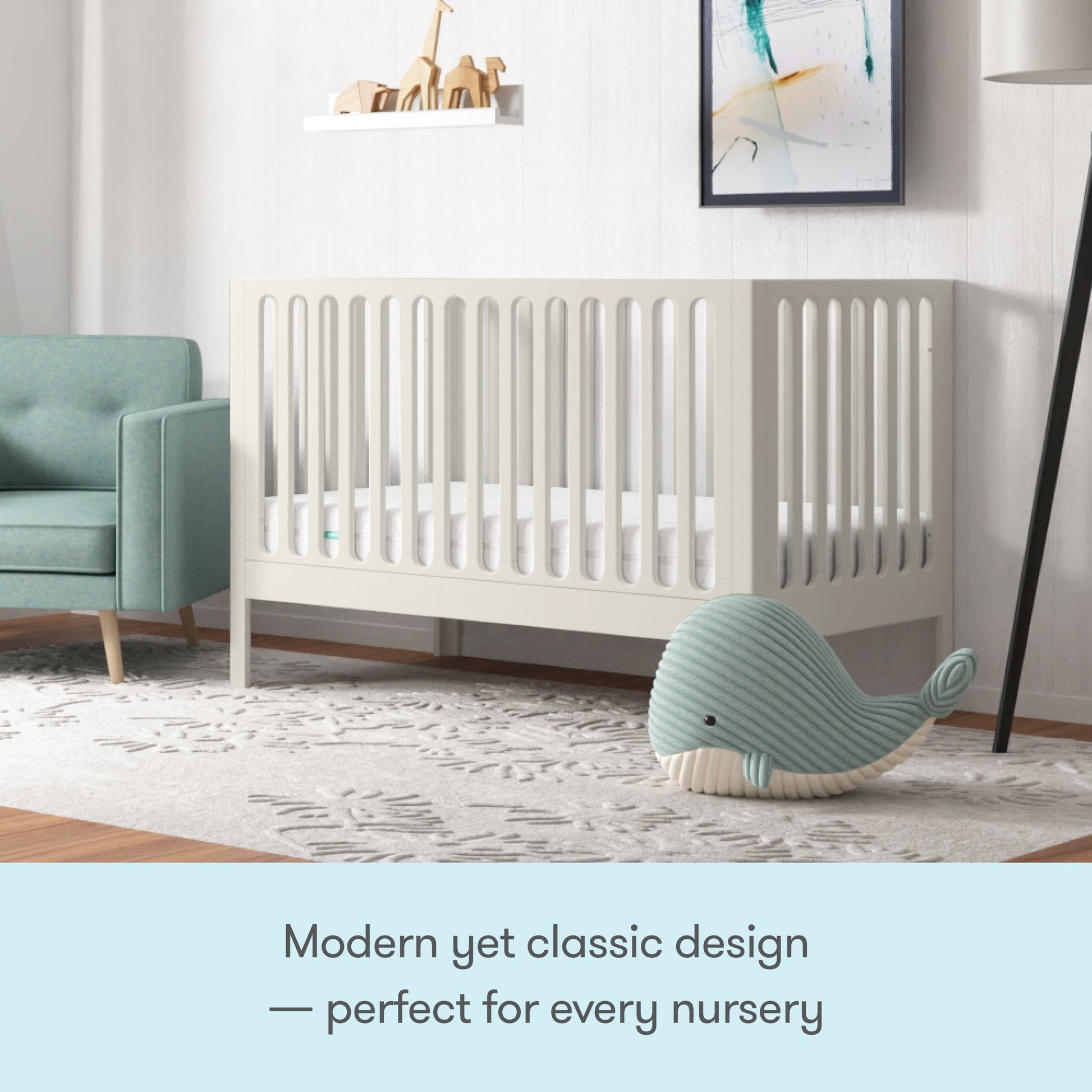 A modern nursery featuring the Newton Galileo Convertible Crib by Newton Baby, a light green armchair, patterned rug, plush blue whale toy, and wall shelves with decor. Modern yet classic design—perfect for every nursery.