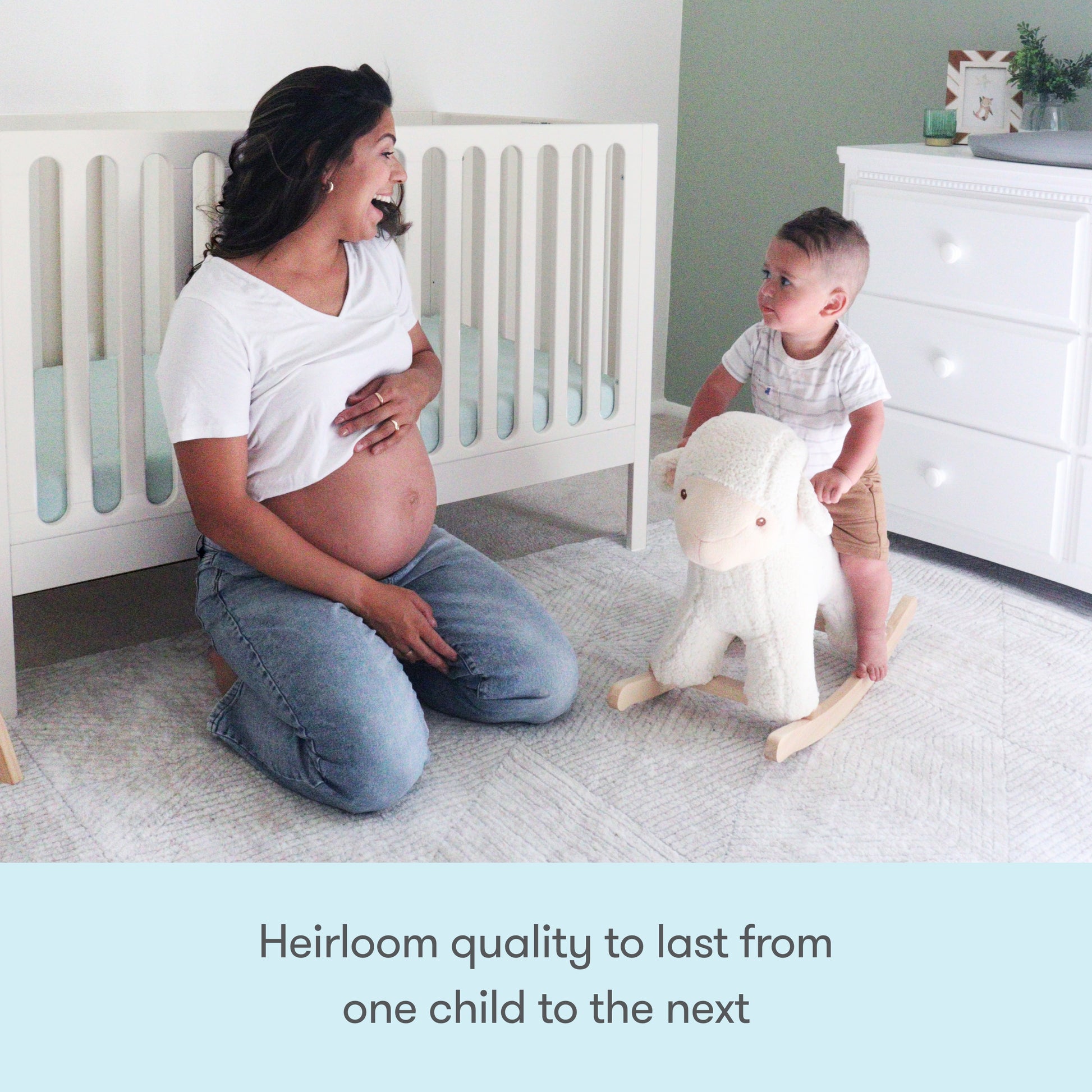 A pregnant woman smiles at a toddler riding a plush rocking sheep in a bright nursery with the Newton Galileo Convertible Crib by Newton Baby. Text below reads, Heirloom quality to last from one child to the next.