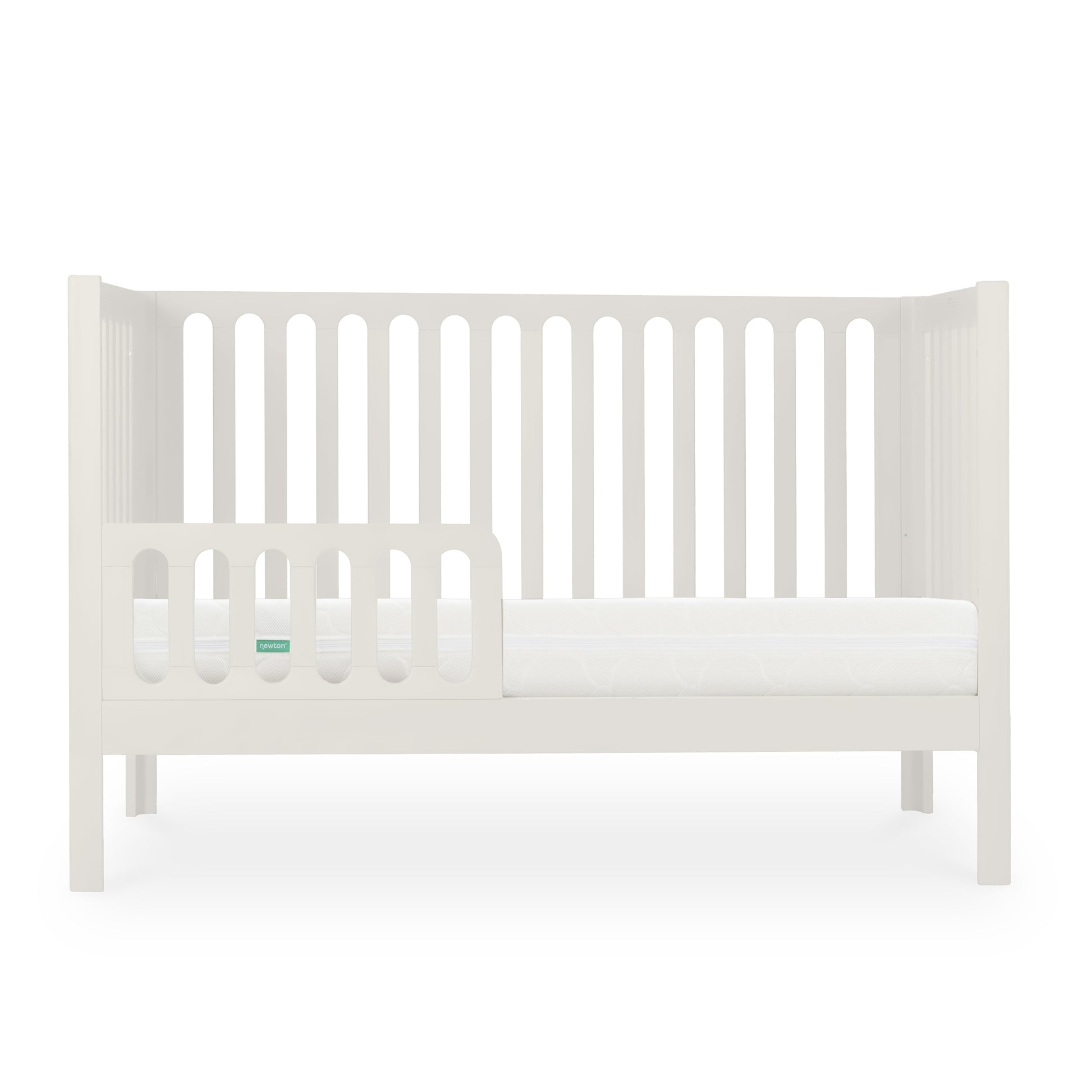 The Newton Galileo Convertible Crib by Newton Baby features white beech wood, vertical slats, an open side with a toddler rail, and a white mattress that showcases its toddler bed conversion against a plain white background.