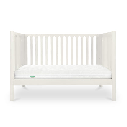 The Newton Galileo Convertible Crib by Newton Baby features white beech wood with vertical slats and a white mattress, set against a plain background. It easily converts from crib to toddler bed to suit your child’s needs.