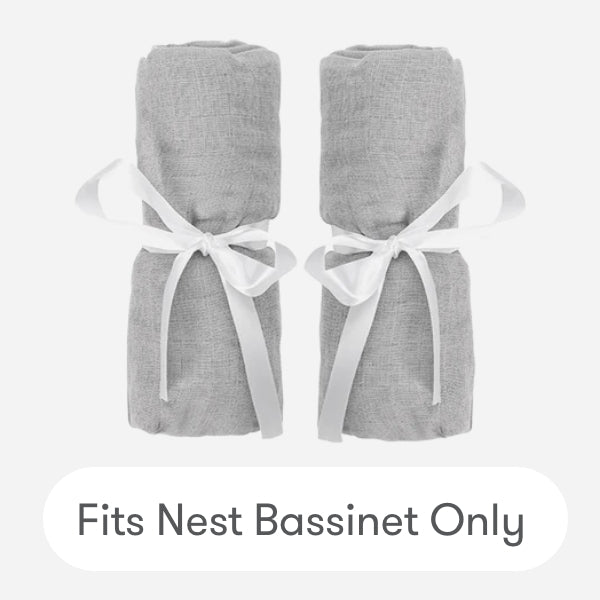 Two gray cotton muslin Nest Bassinet Extra Sheets by Newton Baby, rolled and tied with white ribbons, side by side on a light background. Text below: Fits Nest Bassinet Only—perfect breathable crib sheets for your baby.