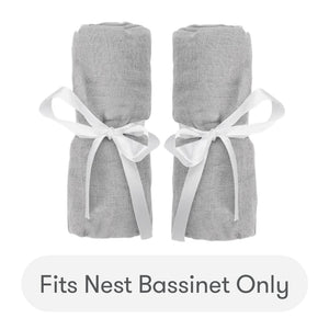 Two rolled gray Newton Baby Nest Bassinet Extra Sheets, tied with white ribbons and placed side by side. Text below reads: Fits Nest Bassinet Only. skip