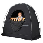 Baby in crib peeking out through window into slumberpod tent, big black tent over wooden crib with baby inside. skip