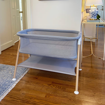 Gray essential bassinet in neutral room with blue rug