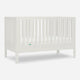 The Newton Galileo Convertible Crib by Newton Baby is a white beech wood crib with vertical slats and a mattress, designed for easy toddler bed conversion, shown against a plain white background.