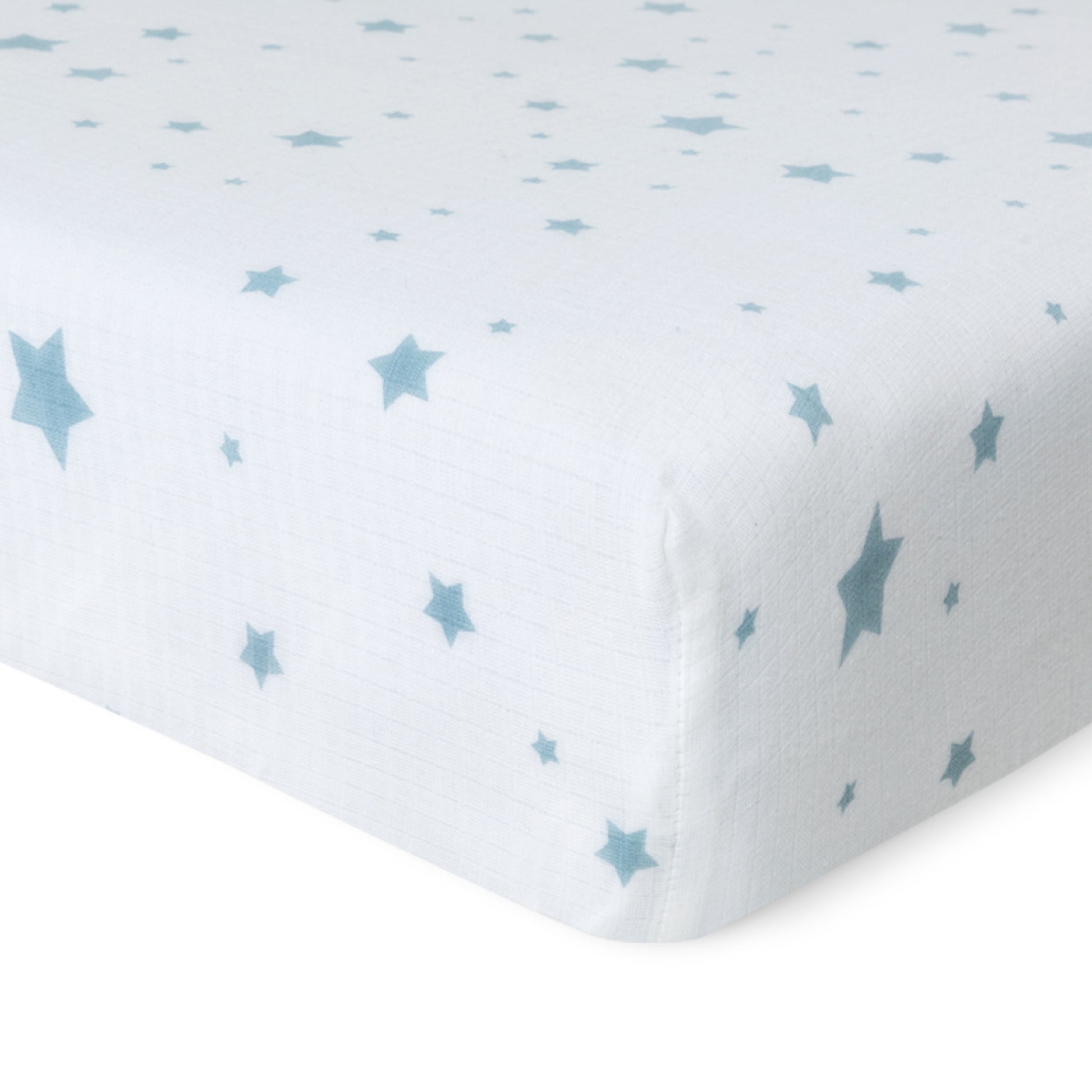 Close-up of Newton Baby’s Breathable, Organic Cotton Sheets (2-pack), showing a white muslin sheet with light blue stars in various sizes, snugly fitted on the mattress and set against a plain white background.