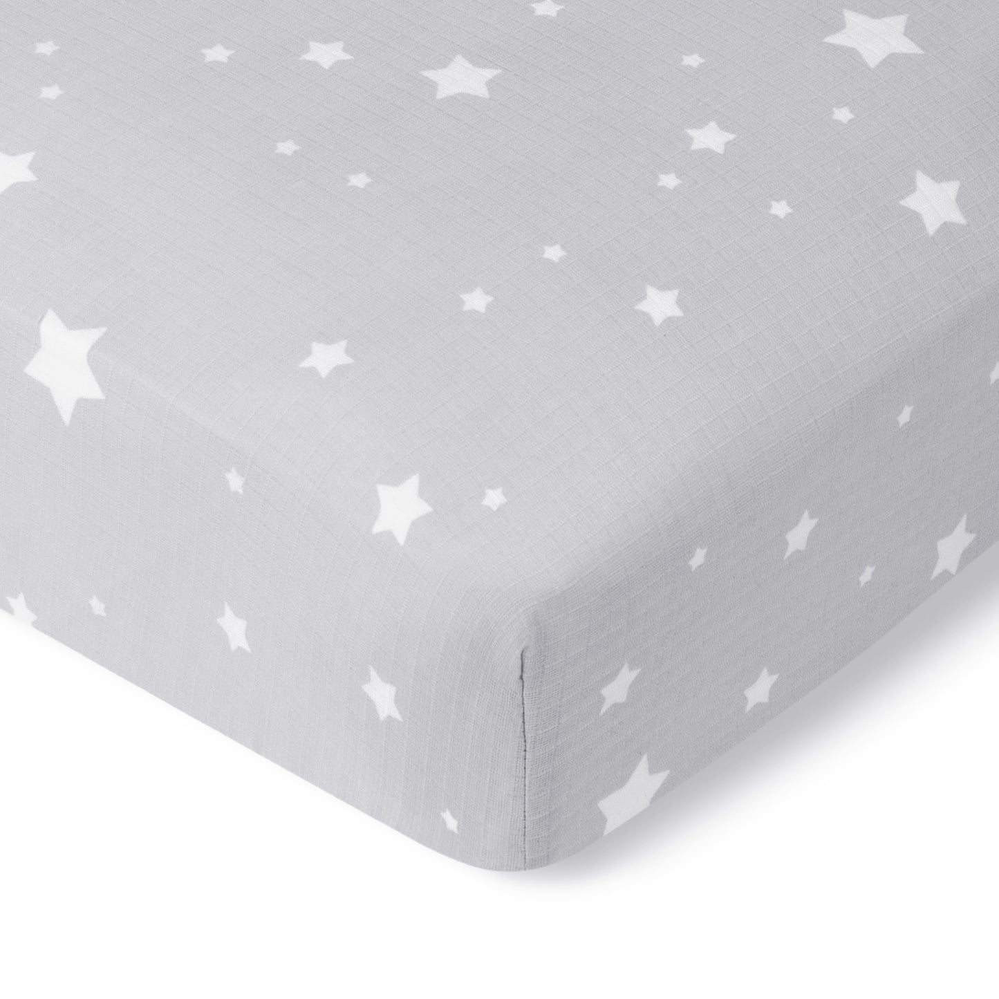 A close-up of Newton Baby’s Breathable, Organic Cotton Sheets (2-pack) in gray with a white star pattern and subtle grid texture covers the mattress corner, showcasing their soft, smooth look.