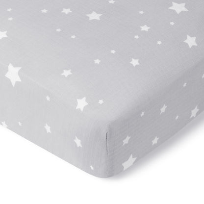 A close-up of Newton Baby’s Breathable, Organic Cotton Sheets (2-pack) in gray with a white star pattern and subtle grid texture covers the mattress corner, showcasing their soft, smooth look.