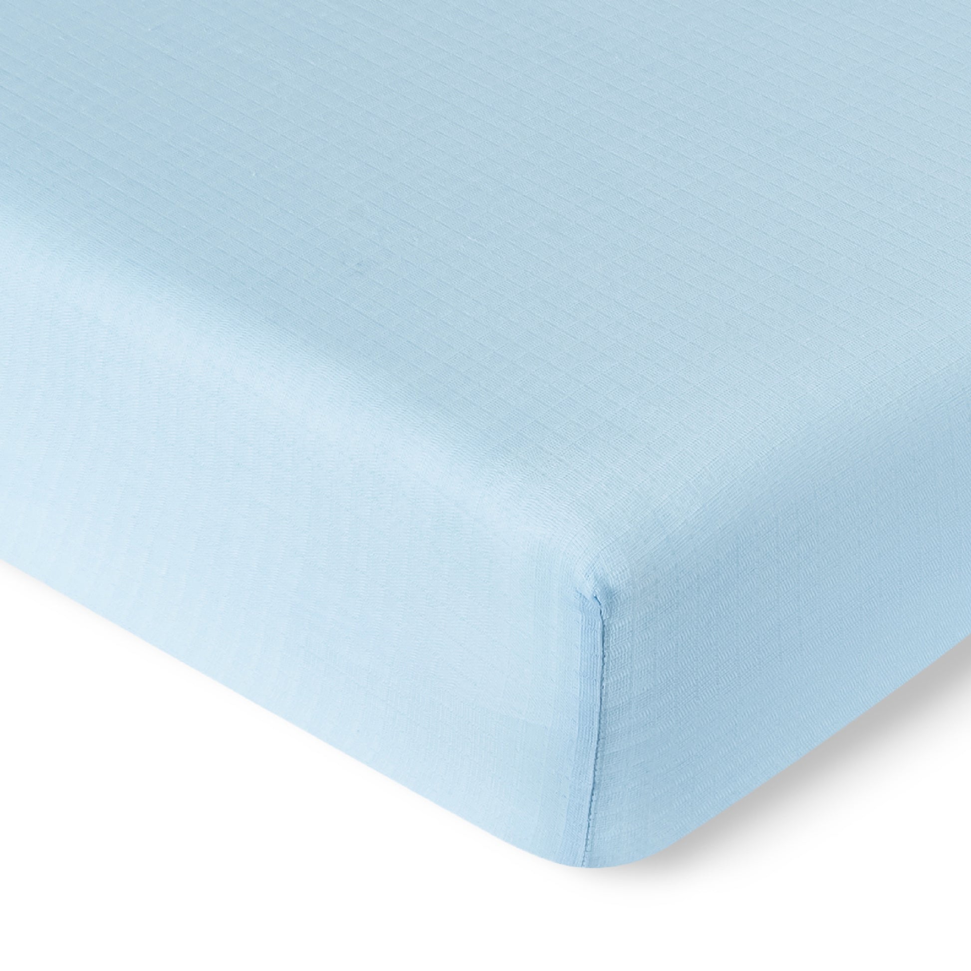 Close-up of the corner of a Newton Baby Breathable, Organic Cotton Sheet (from the 2-pack), in light blue, covering a mattress. The image highlights the smooth, slightly textured fabric and neatly finished seams.