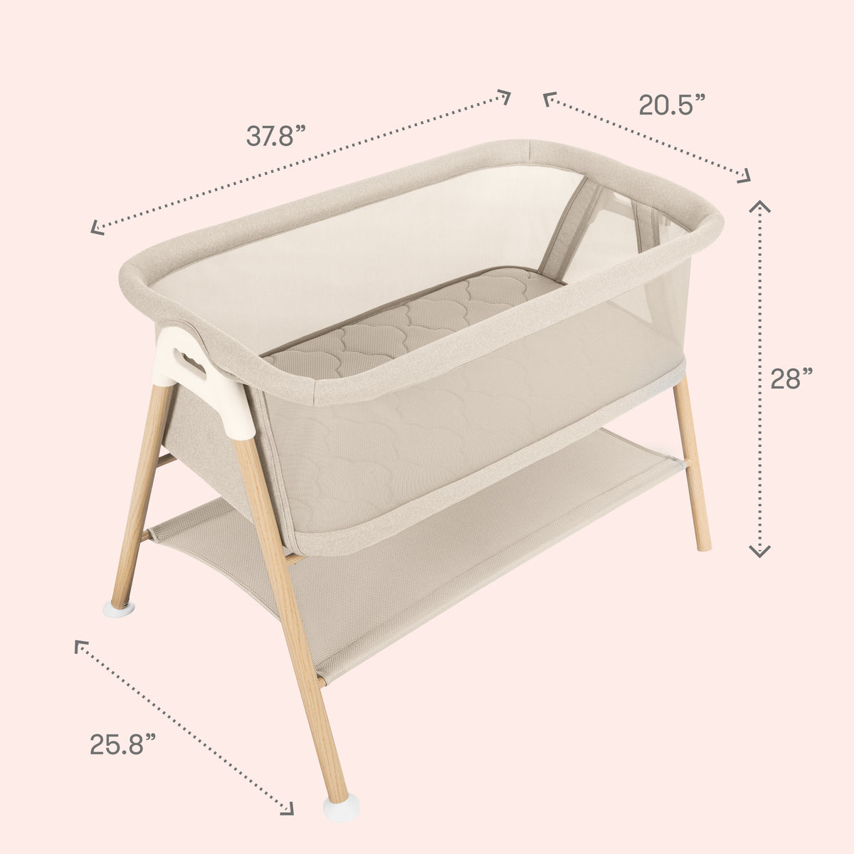 The Newton Baby Essential Bassinet in beige showcases breathable mesh sides, sturdy wooden legs, and a handy lower storage shelf. Measuring 37.8″ long, 20.5″ wide, and 28″ high with legs spaced 25.8″ apart, it is displayed on a soft pale pink background for an elegant touch.