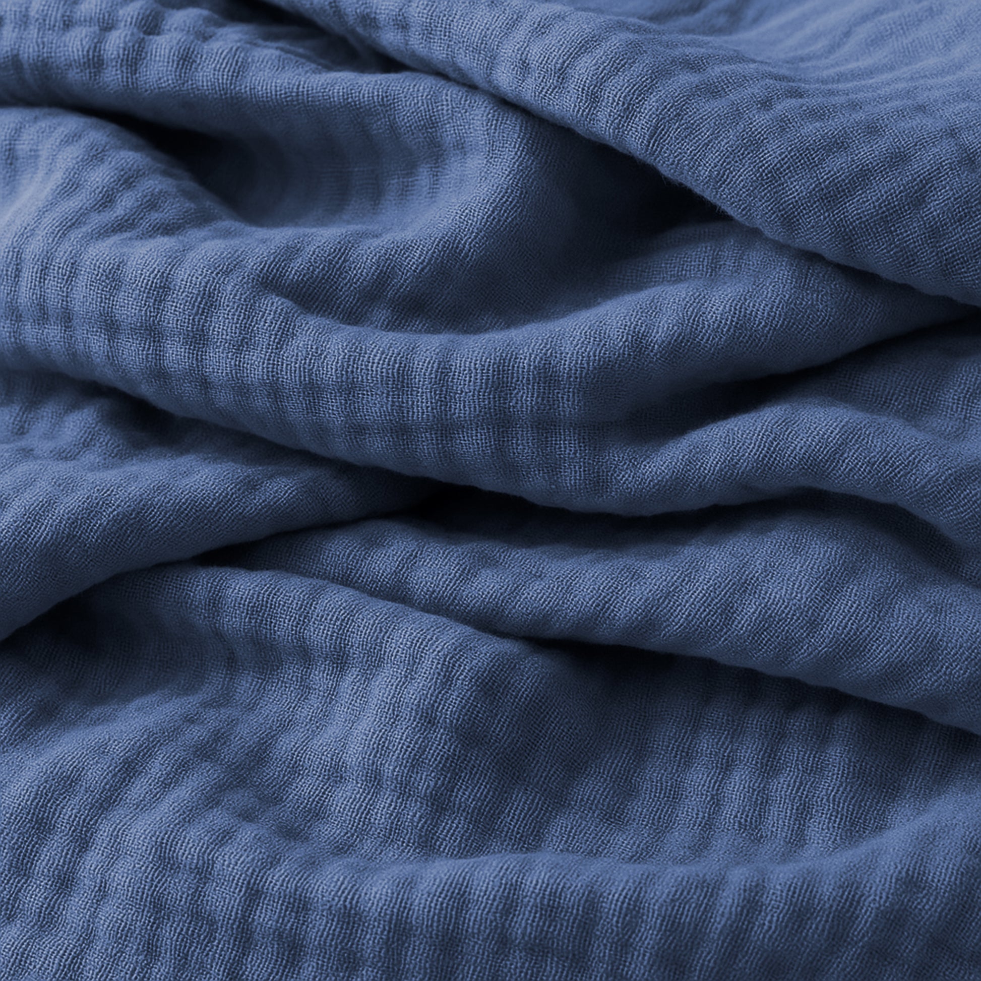 Close-up of soft, crumpled Newton Baby Breathable, Organic Cotton Sheets (2-pack) in blue, featuring a textured, waffle-like pattern and gentle folds throughout.