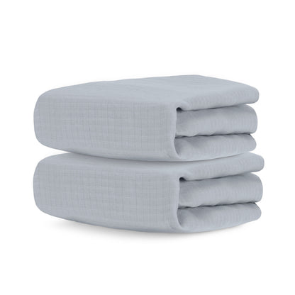 Two neatly folded, light gray Newton Baby Breathable, Organic Cotton Sheets (2-pack) with a subtle textured grid pattern—ideal for layering in the crib.