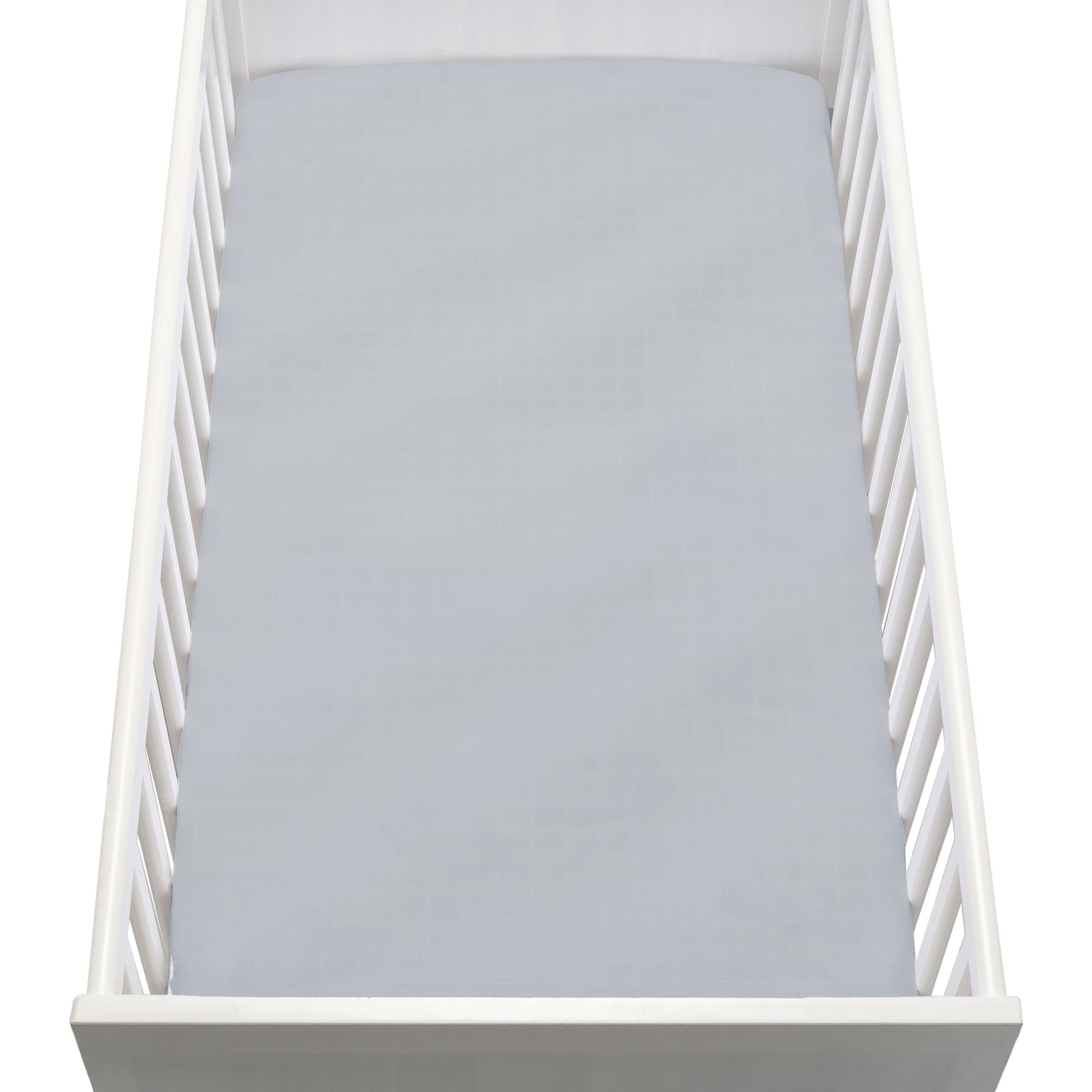 A white baby crib with vertical slats features a Newton Baby Breathable, Organic Cotton Sheet (2-pack) in light gray covering the mattress, viewed from above.