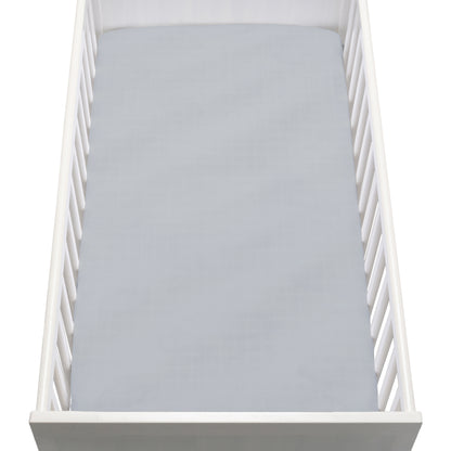 A white baby crib with vertical slats features a Newton Baby Breathable, Organic Cotton Sheet (2-pack) in light gray covering the mattress, viewed from above.