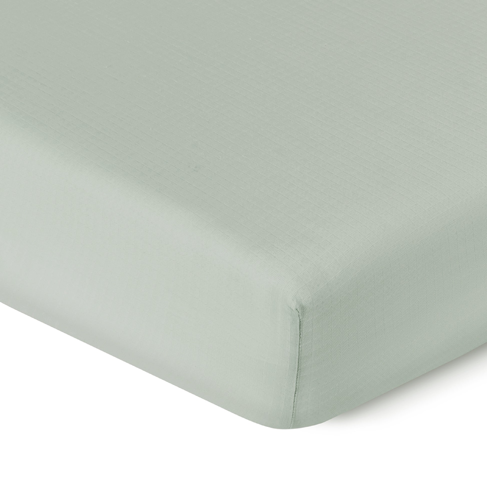 Close-up of a Newton Baby Breathable, Organic Cotton Sheet (2-pack) in light green, smoothly covering a crib mattress corner with its subtle textured pattern and snug fit.