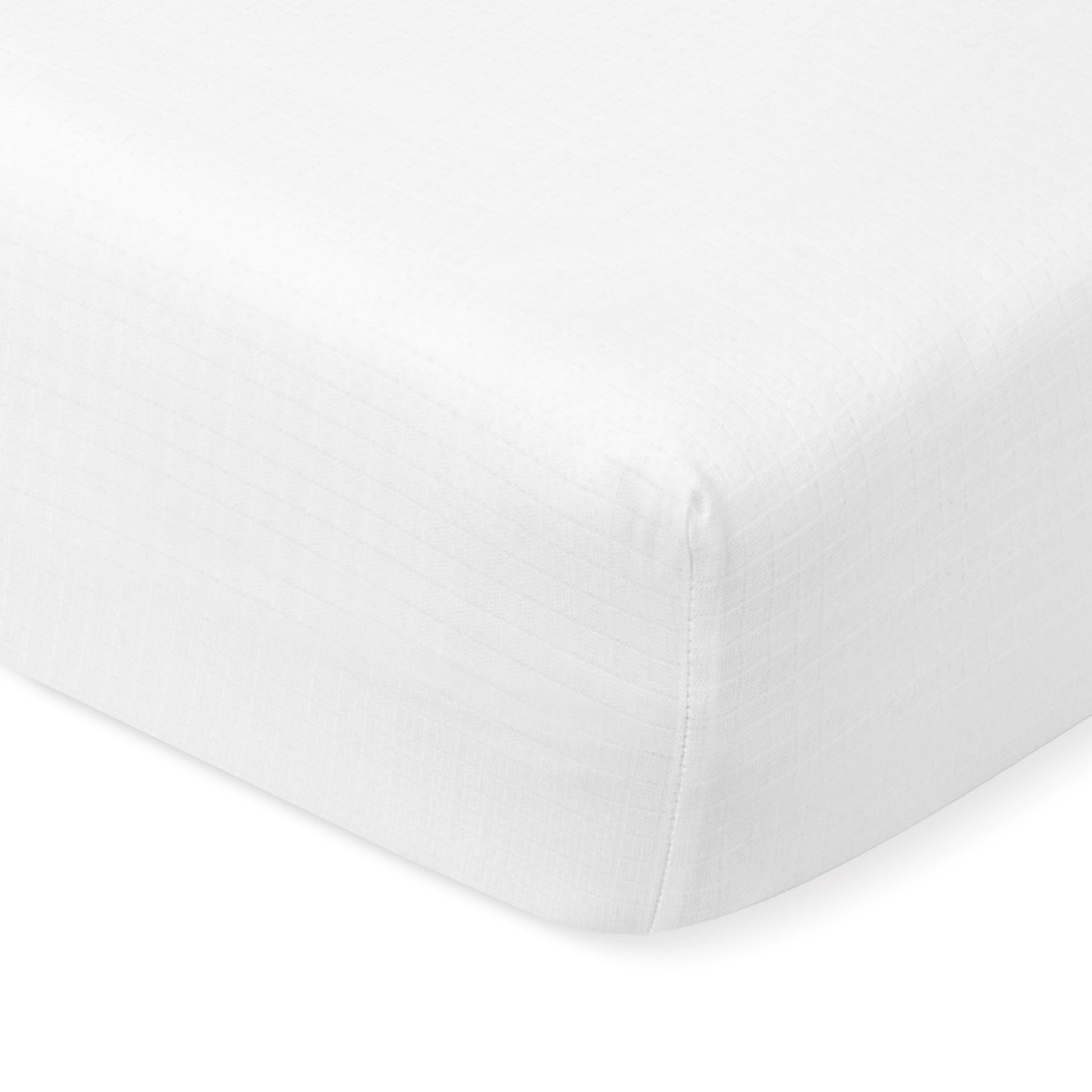 Close-up of a white, fitted Newton Baby Breathable, Organic Cotton Sheet (2-pack) with a subtle checkered pattern, tightly stretched over the corner of a crib mattress.