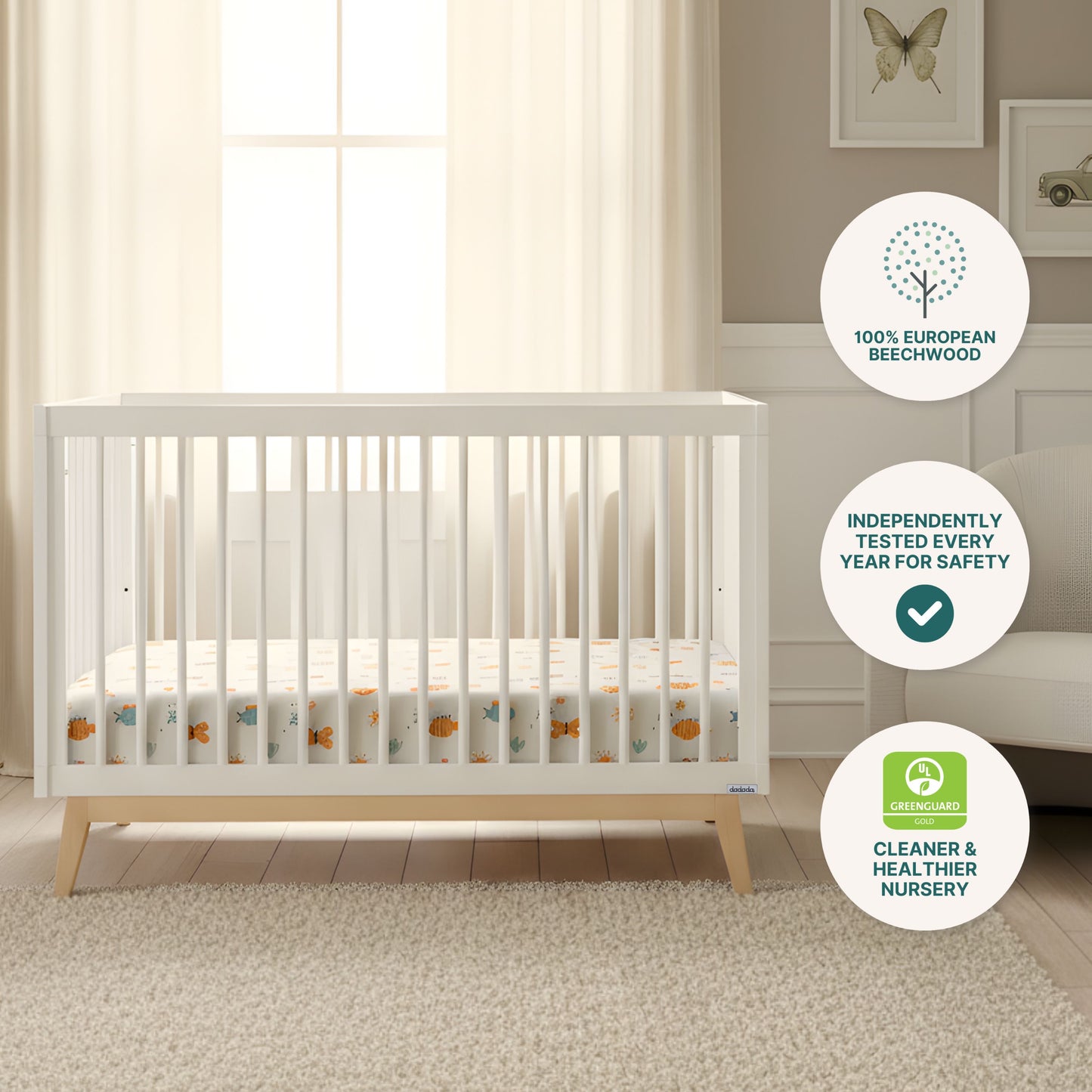 The Soho Convertible Crib by dadada baby features sturdy beechwood in a cozy nursery with cream curtains, beige armchair, rug, and wall art. Badges highlight beechwood construction, safety testing, and GREENGUARD certification.