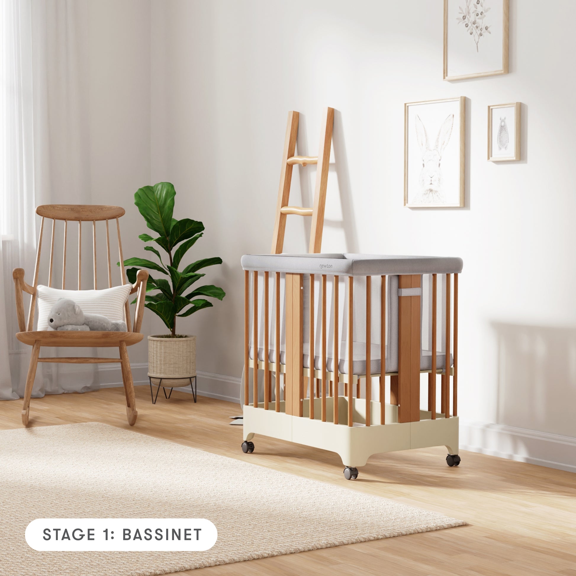 Natural + Dove White color Newton Nest Convertible Crib in bassinet setting with mesh liner, in nursery next to rocking chair, with text "Stage 1: Bassinet"