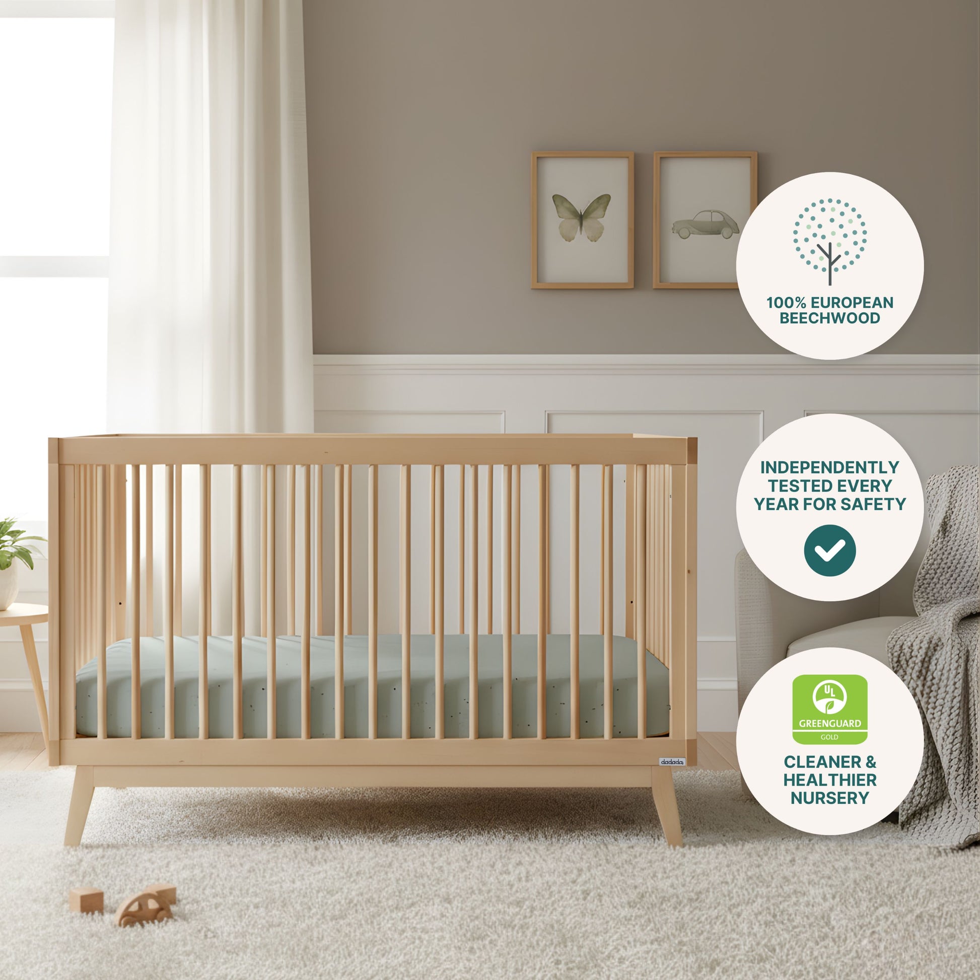 A light wood Soho Convertible Crib by dadada baby with a mint green Newton mattress sits on a beige rug in a neutral nursery. Info bubbles note its beechwood, annual safety testing, and GREENGUARD certification. Framed art hangs nearby.