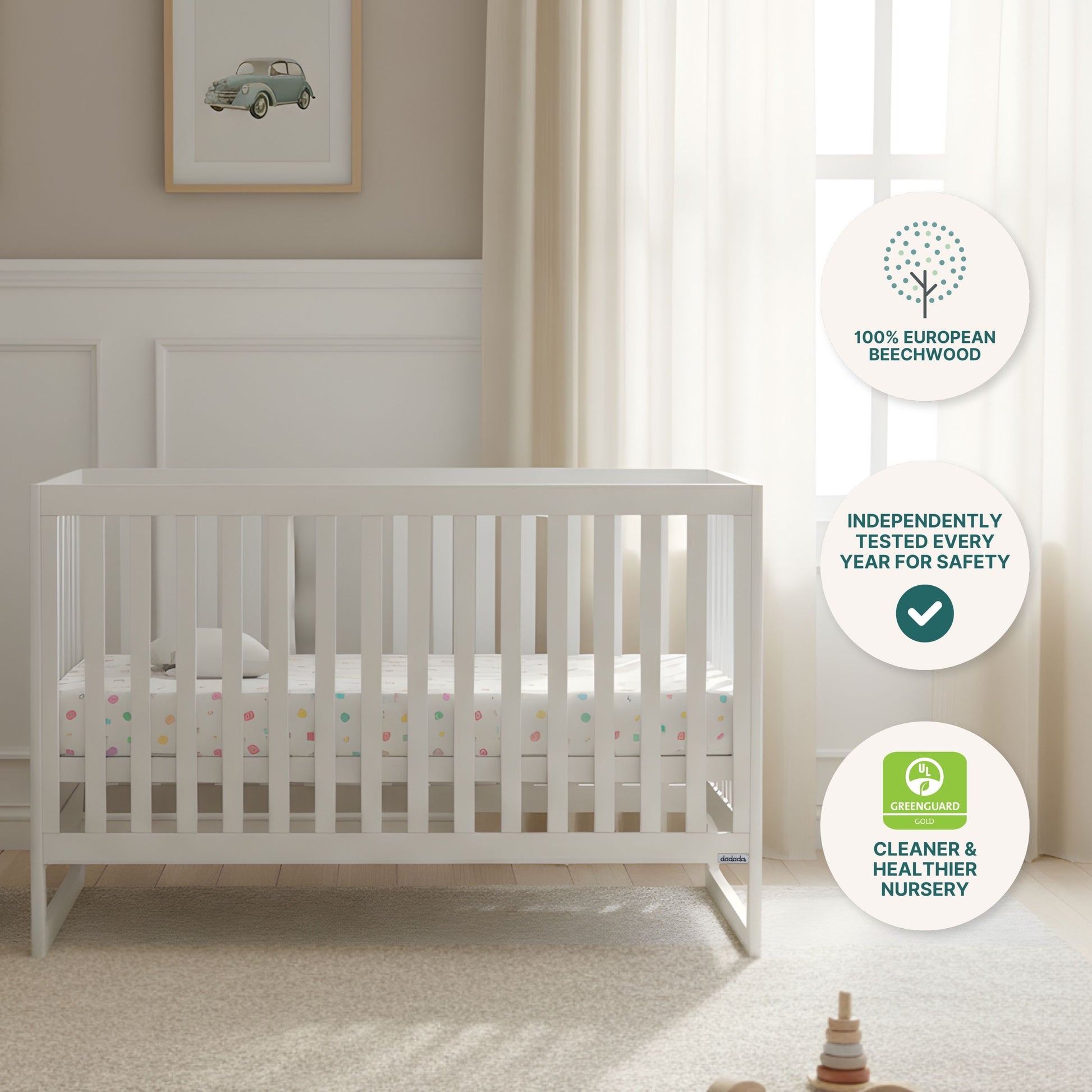 A bright nursery features the dadada baby Austin Convertible Crib in white with a Newton crib mattress, cream curtains, car wall art, and three circular icons for sustainable beechwood, safety testing, and GREENGUARD certification.