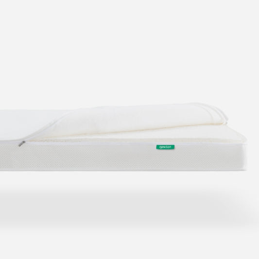 Side view of a Newton baby mattress with a removable cover, featuring a visible "newton" logo on the side.