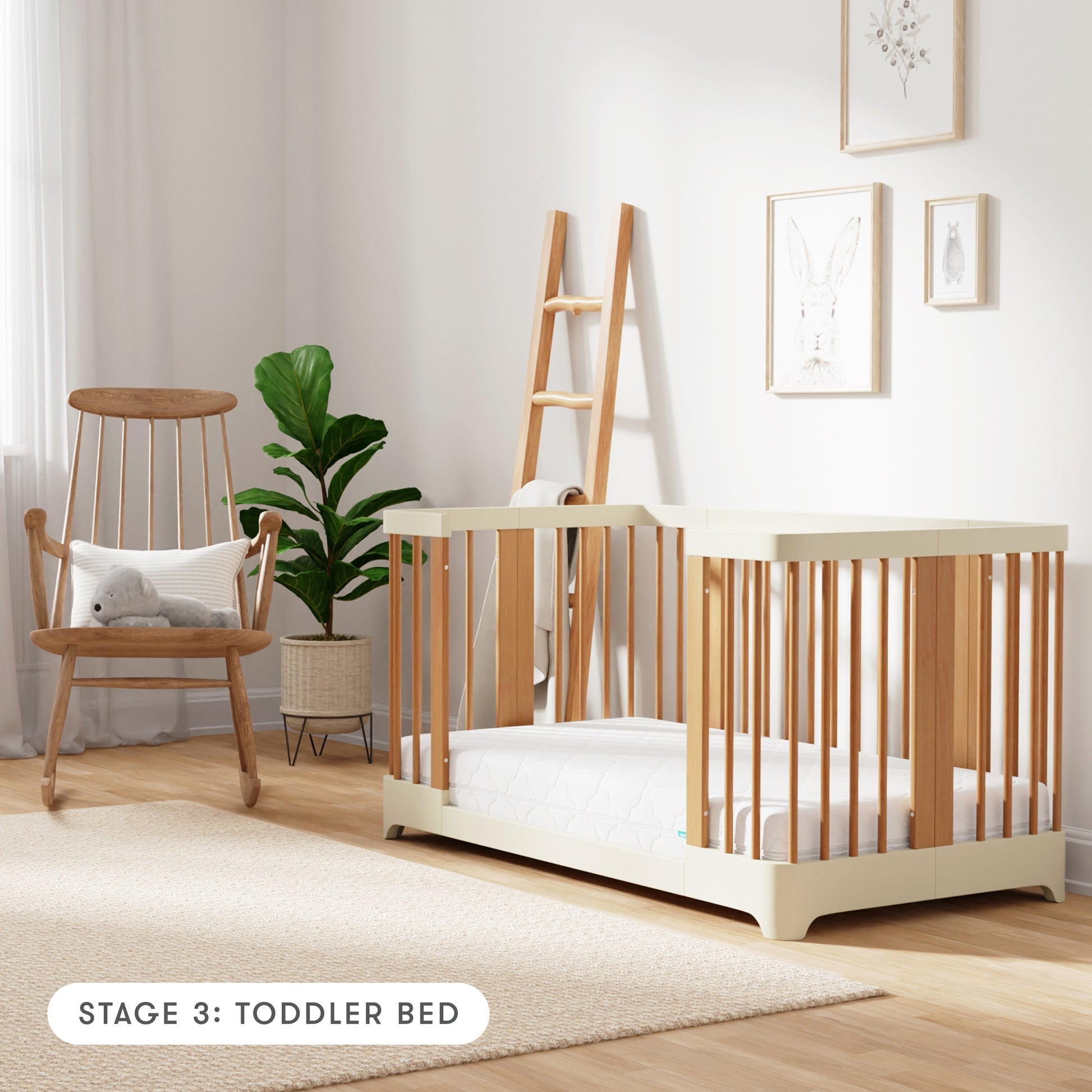 Natural + Dove White color Newton Nest Convertible Crib in toddler bed setting, in nursery next to rocking chair, with text "Stage 3: Toddler Bed"