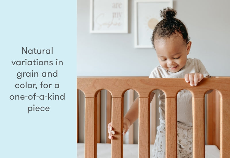 Toddler smiling while standing in a crib with the text "Natural variations in grain and color, for a one-of-a-kind piece".