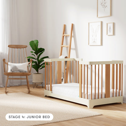 Natural + Dove White color Newton Nest Convertible Crib in Junior Bed setting, in nursery next to rocking chair, with text "Stage 4: Junior Bed"