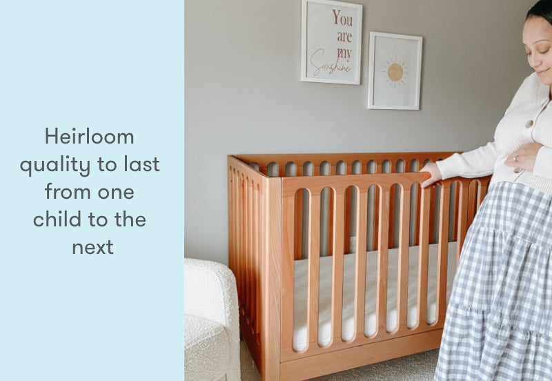A smiling woman touches a wooden crib in a nursery, next to text that reads "Heirloom quality to last from one child to the next."