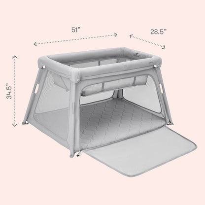 The Newton Baby Deluxe Travel Crib & Play Yard, shown in gray with mesh sides and a quilted breathable mattress, is displayed on a light pink background. The open front flap reveals dimensions: 51”W x 28.5”D x 34.5”H.