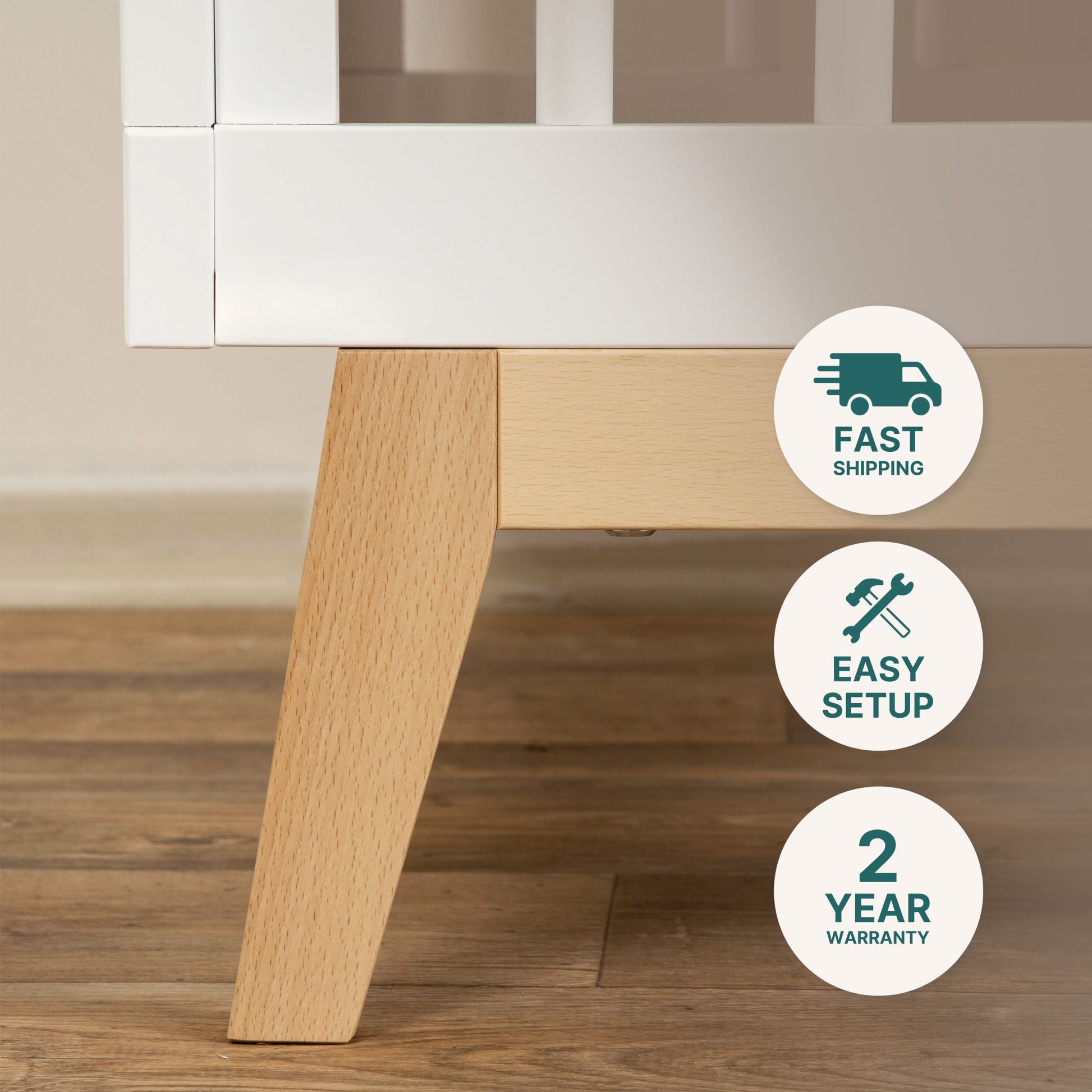 Close-up of a Soho Convertible Crib leg by dadada baby on hardwood floor. Three icons to the right show fast shipping, easy setup, and a 2-year warranty.