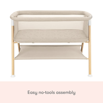 The Newton Baby Essential Bassinet features a beige, non-toxic design with wooden legs, mesh sides, a lower storage shelf, and easy no-tools assembly.
