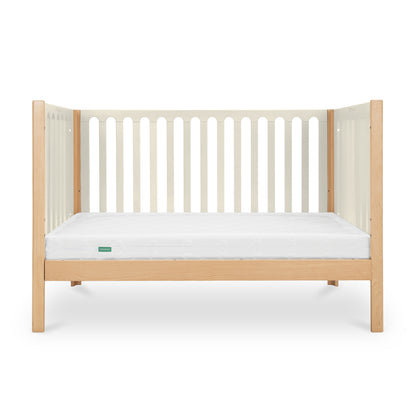 The Newton Galileo Convertible Crib by Newton Baby features beech wood legs and side panels, white vertical slats, and a white mattress, shown on a plain white background. Easily adapts to a toddler bed as your child grows.