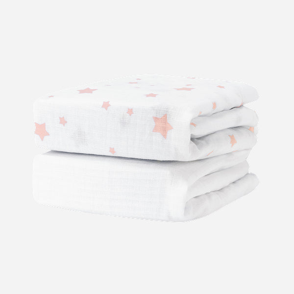 Two folded Newton Baby Breathable, Organic Cotton Sheets (2-pack), featuring a pink star pattern, are stacked together against a plain white background.