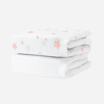 Two folded Newton Baby Breathable, Organic Cotton Sheets (2-pack), featuring a pink star pattern, are stacked together against a plain white background.